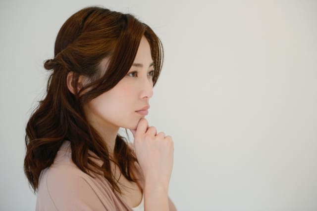 顎に手を置いて考える女性