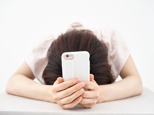 スマホをもってうつむく女性